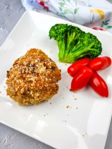 Vertical shot of a copycat HelloFresh Crispy Shallot Croquettes on a white plate with tomatoes and broccoli.
