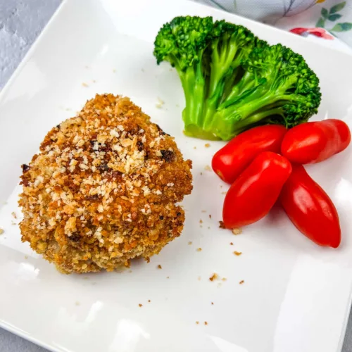 Vertical shot of a copycat HelloFresh Crispy Shallot Croquettes on a white plate with tomatoes and broccoli.