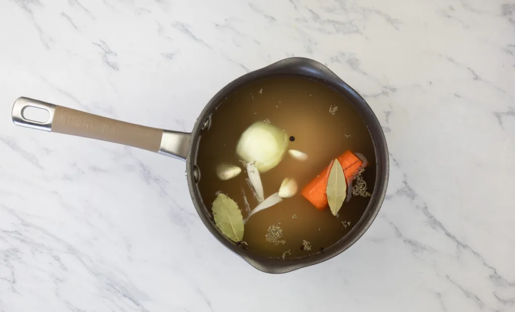 Broth, chicken and vegetables in a pot.