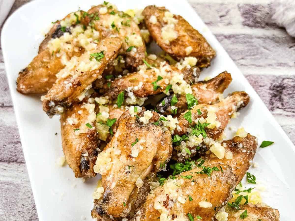 Chicken wings with garlic and Parmesan on a white plate.