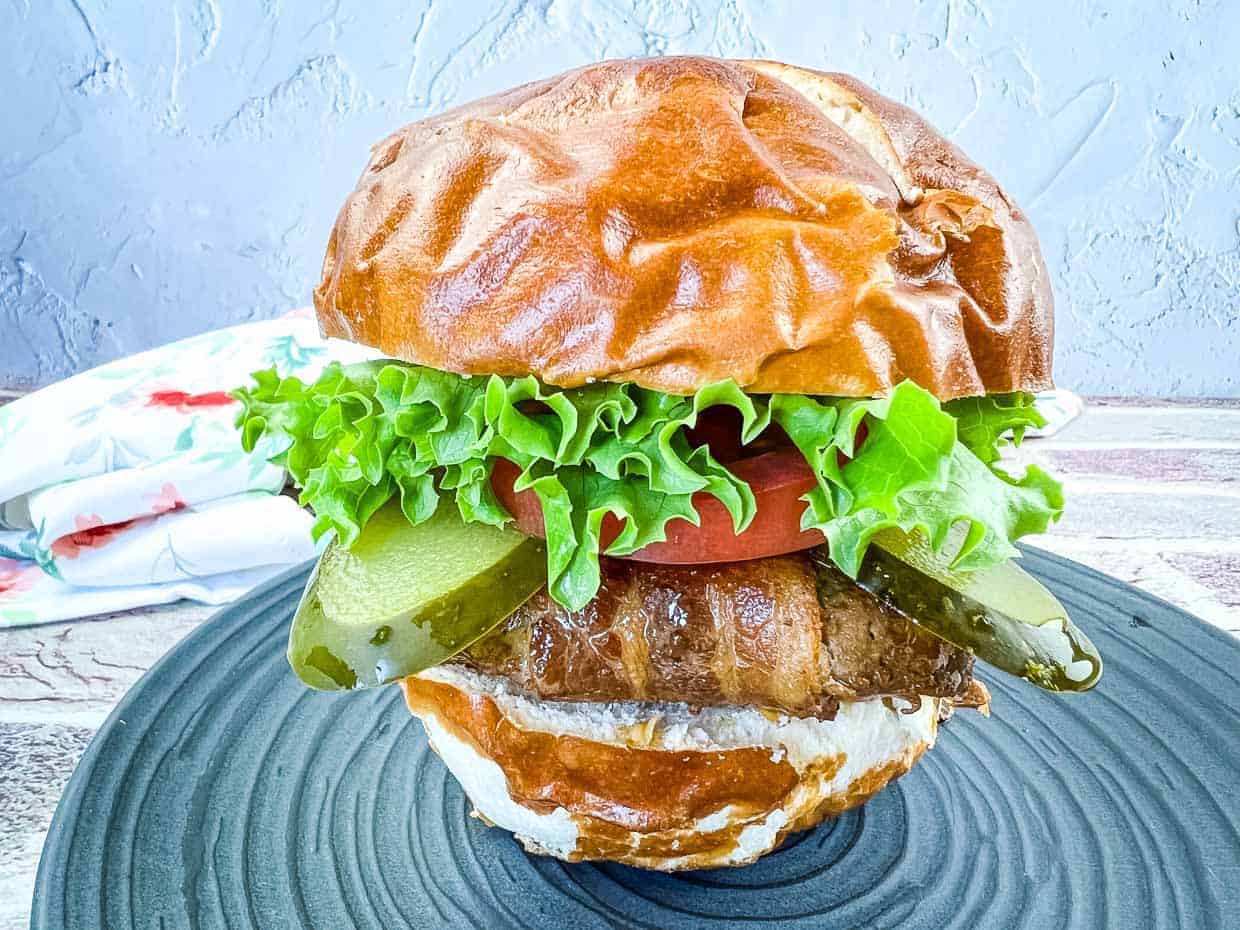 Bacon-Wrapped Burger on a black plate.