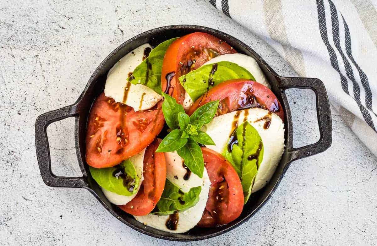 A top-down shot of a classic caprese salad in a black dish.