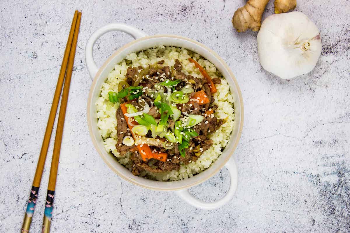 A top-down shot of Korean Beef Bowl with chopsticks and garlic.