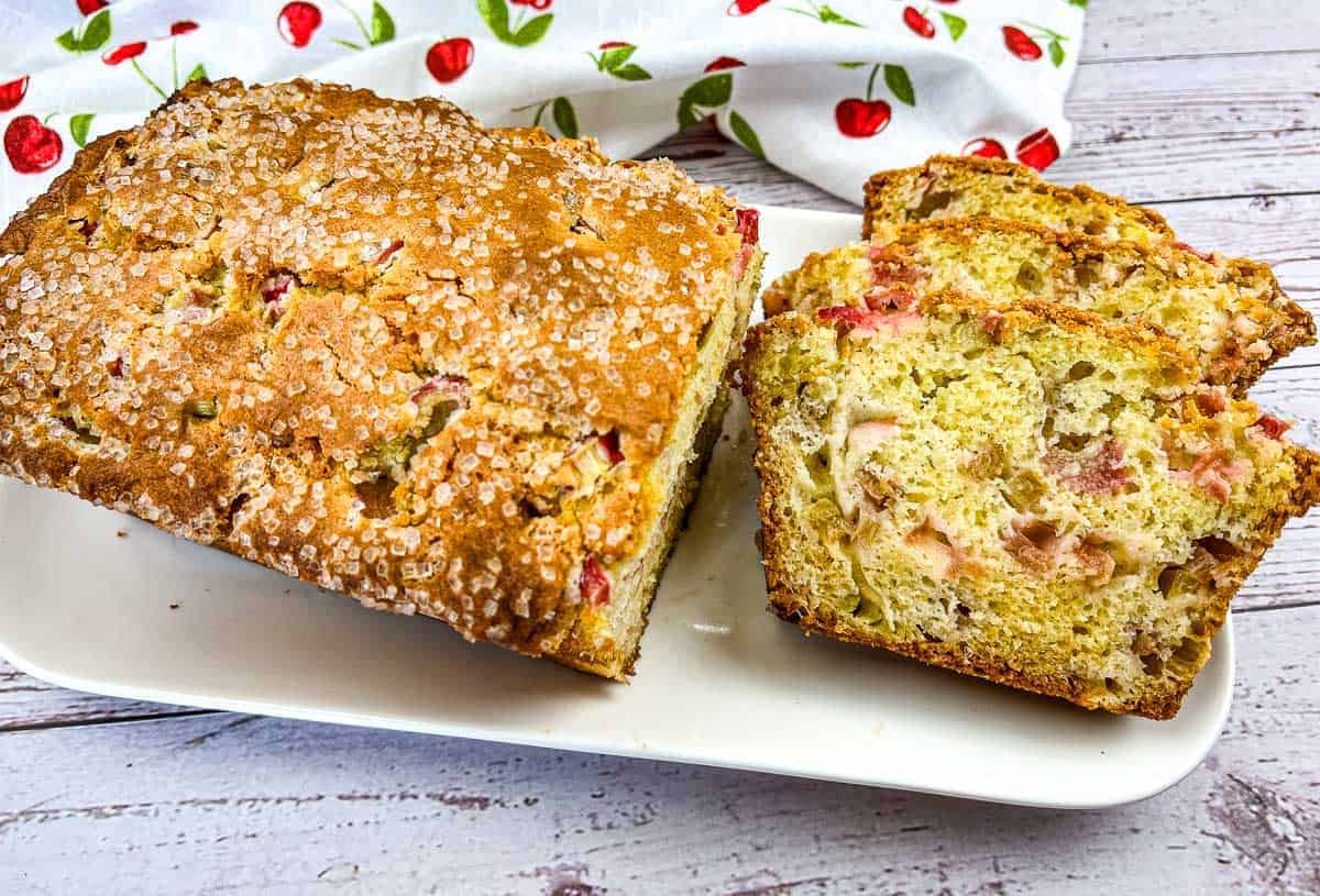 A loaf of Rhubarb Bread with a few slices on a white plate.