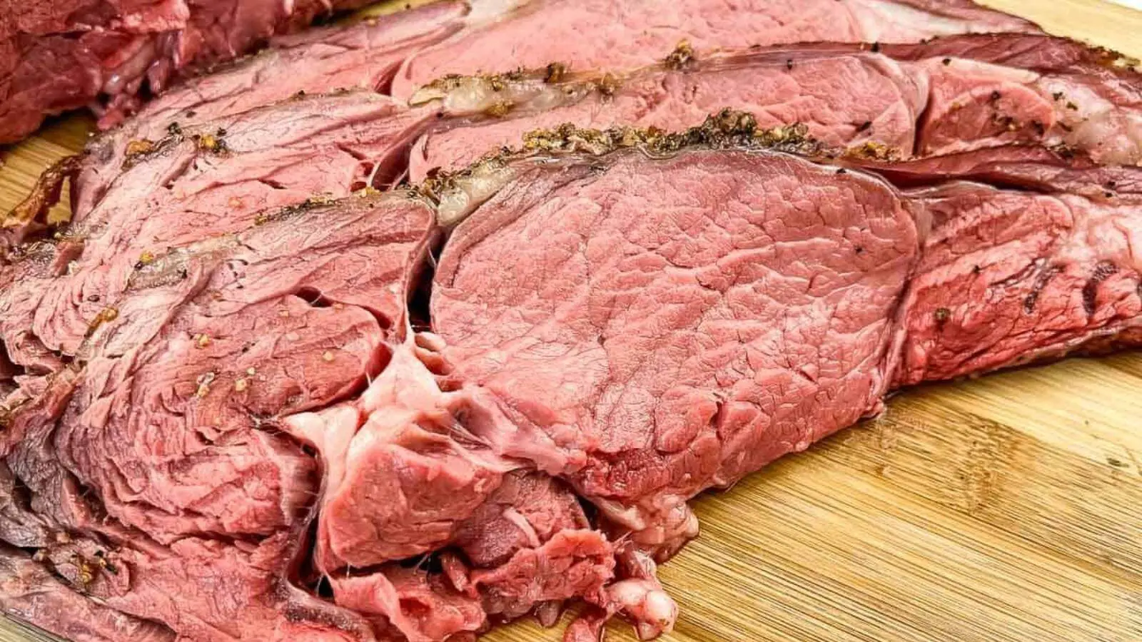 Sliced smoked ribeye beef on a cutting board.