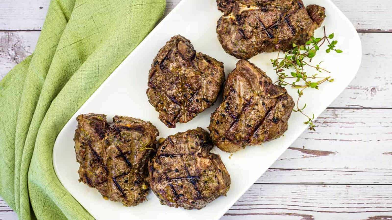 Smoked lamb chops on a white plate with a green napkin.