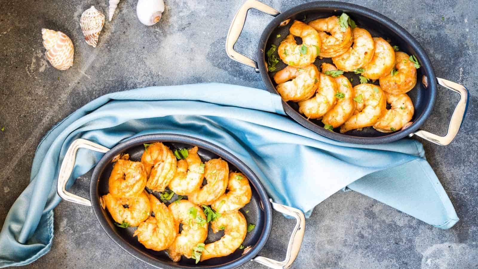 Two pans of smoked shrimp on a table.