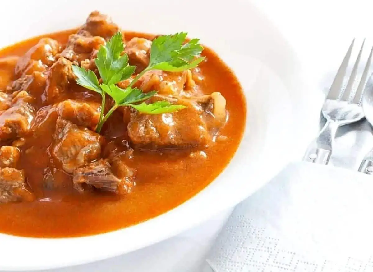 Beef stew in a white bowl with a fork.