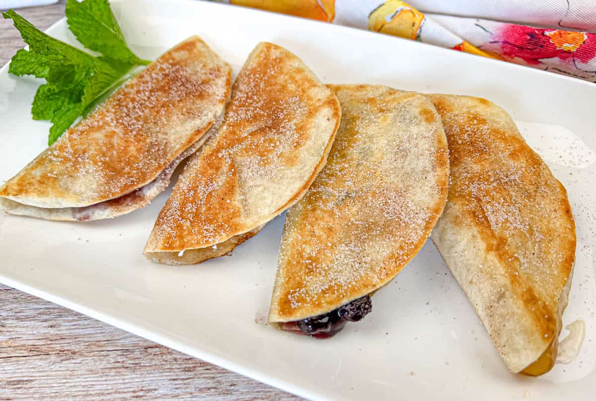 Four pieces of Fruit Quesadillas on a white plate.