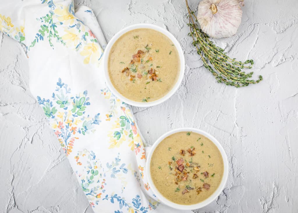 Two bowls of cream of caramelized onion & mushroom soup with garlic and thyme.