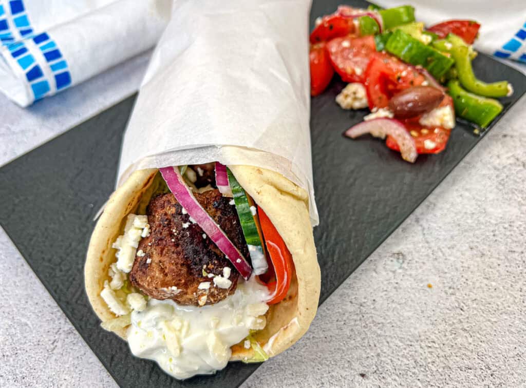 Greek Meatball Pita Sandwich served on a black slate plate.