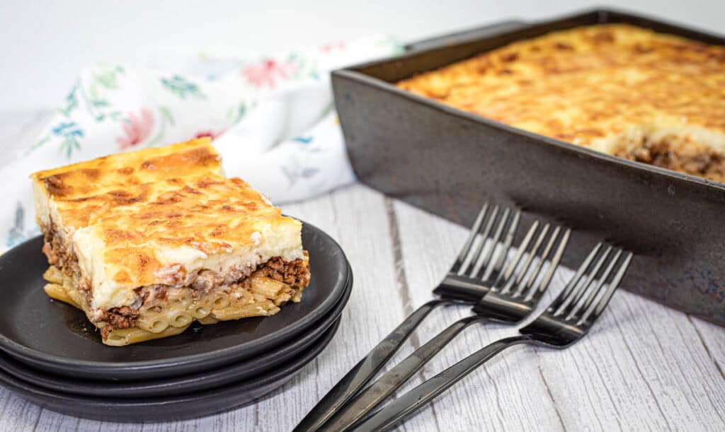 A square piece of pastitsio dish served on a stack of black plates.