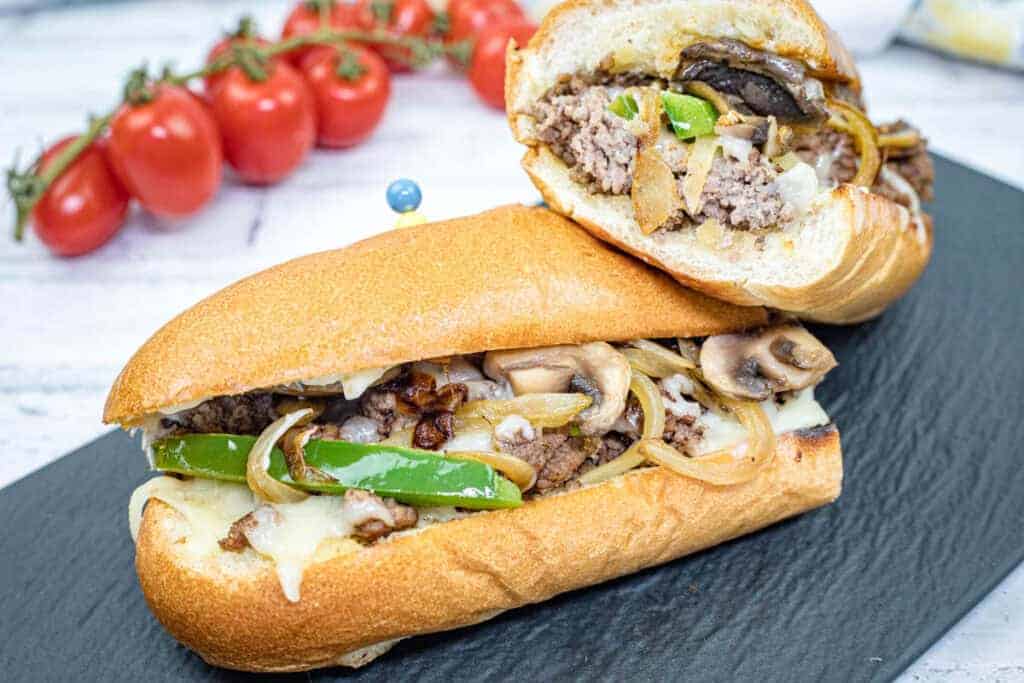 Double halves of Ground Beef Philly Cheesesteak on a slate plate.