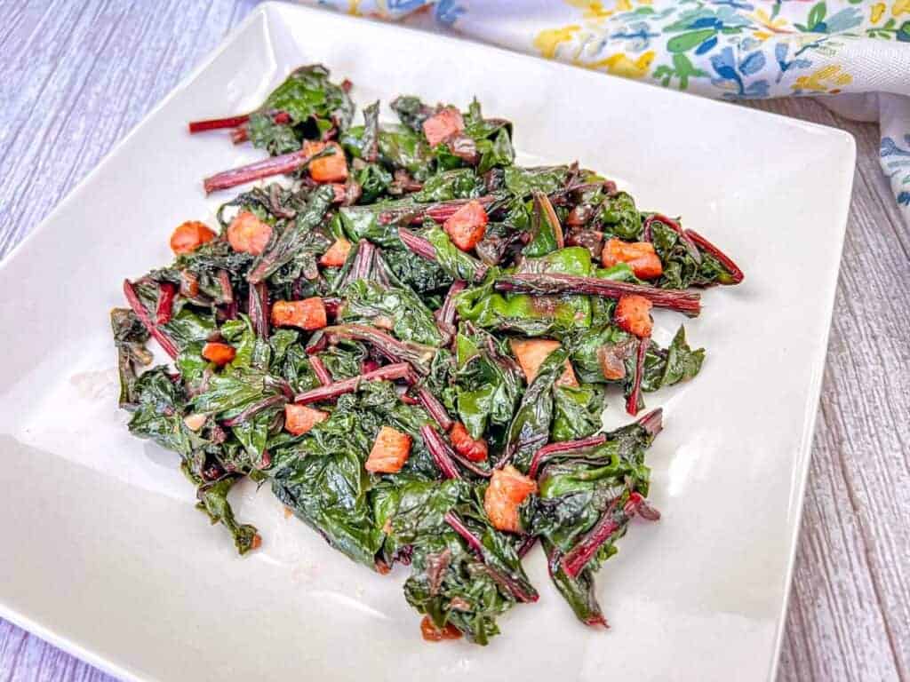 Sauteed Beet Greens with Pancetta on a white plate.