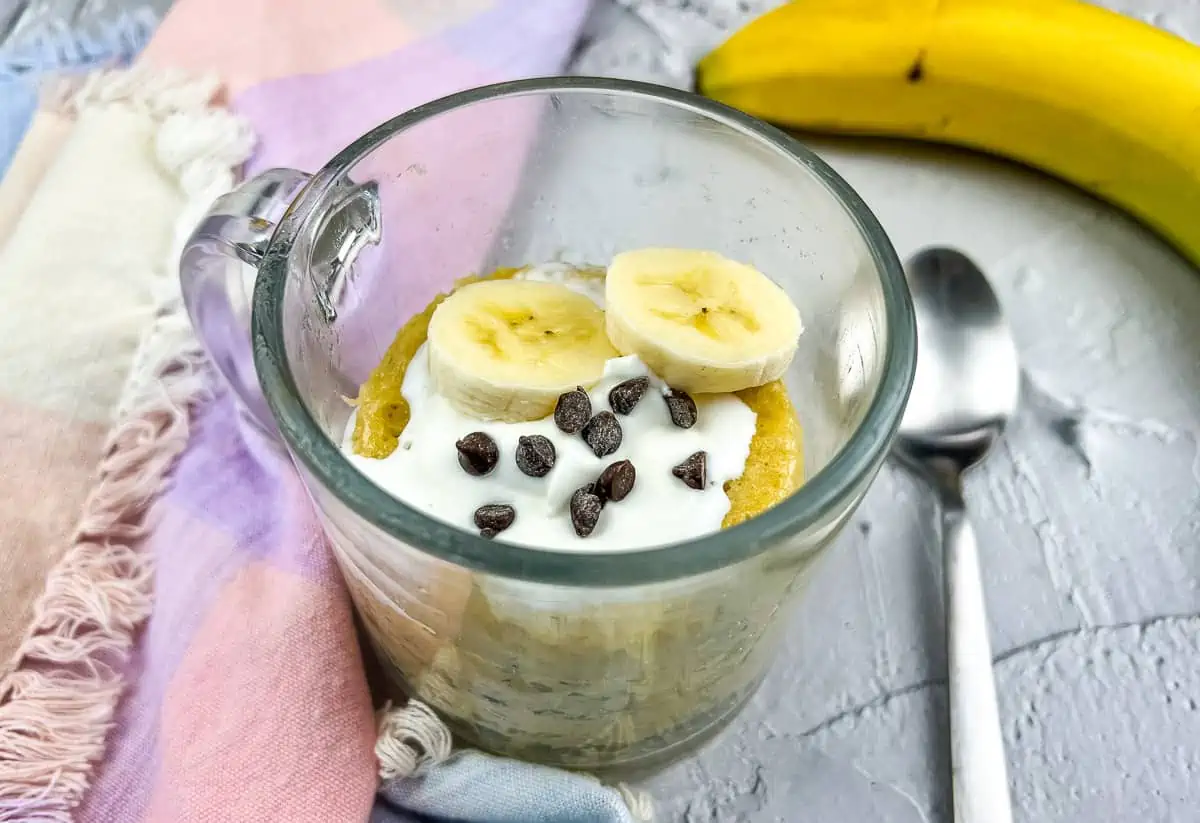 Banana chocolate mug cake with spoon and banana.