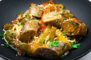 Slow cooker sausage and peppers garnished with grated cheese and chopped parsley.