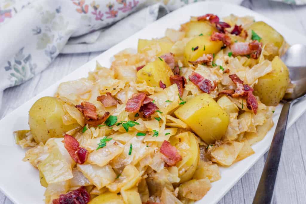 A platter of Cabbage & Potatoes with Bacon and garnished with parsley.