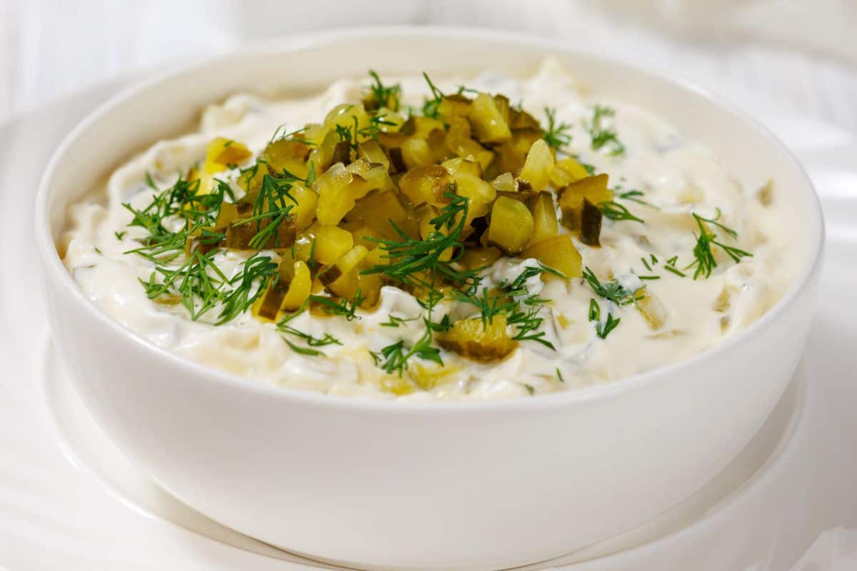 A bowl of Keto Dill Pickle Dip topped with chopped pickles and fresh dill.