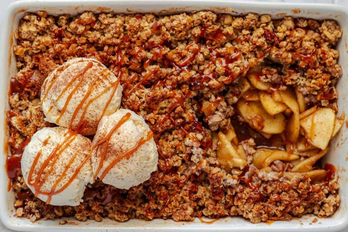 Baked apple-crumble dessert with ice cream and caramel drizzle, homemade cozy fall treat.
