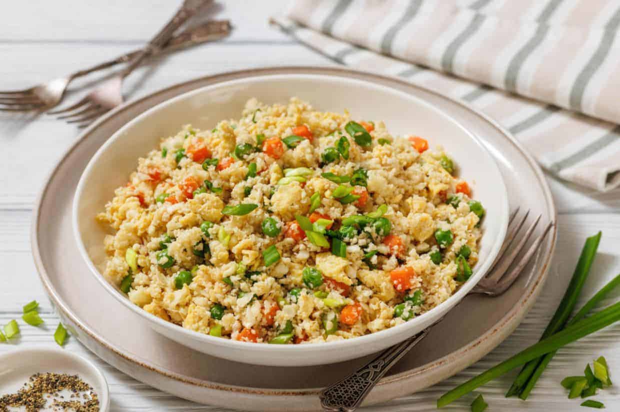 Low Carb Cauliflower Fried Rice served on a plate with a fork and spoon.
